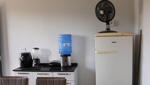 Ett litet, praktiskt kök med kylskåp, kaffebryggare och vattenautomat.