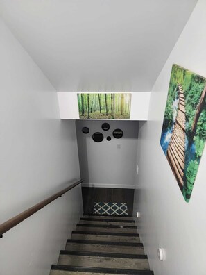 Eine Treppe mit Geländer, einem gemusterten Boden und einer Wand mit einem Kunstwerk zum Thema Natur.