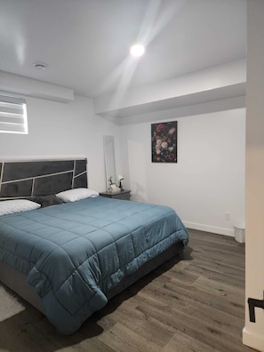Ein Schlafzimmer mit einem Bett, einem Nachttisch, einem Spiegel und einem Bild an der Wand.