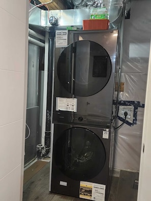 Ein kompakter Waschraum mit zwei Etagen, einer Metallkonstruktion, einem sichtbaren Warmwasserbereiter und einer Steckdose.