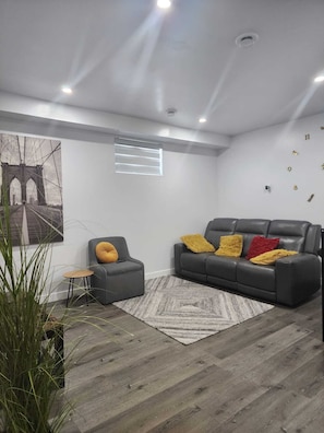 Ein modernes Wohnzimmer mit einem grauen Sofa, einem kleinen Tisch und einem Teppich.