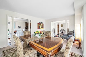 A spacious living room with a large wooden coffee table, patterned sofas, and a vibrant fruit centerpiece.