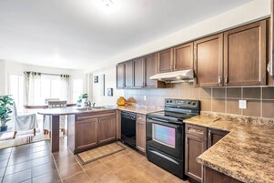 Een moderne keuken met donkerhouten kastjes, een granieten aanrechtblad, een ingebouwde oven en een vaatwasser.
