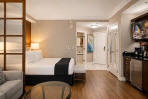 A hotel room with a bed, a seating area, a kitchenette, and a television. - Vegas Strip Studio | Pool & Lazy River (Las Vegas)