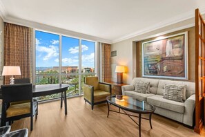 A hotel room with a large window, a sofa, a chair, a coffee table, and a lamp. - Vegas Strip Studio | Pool & Lazy River (Las Vegas)