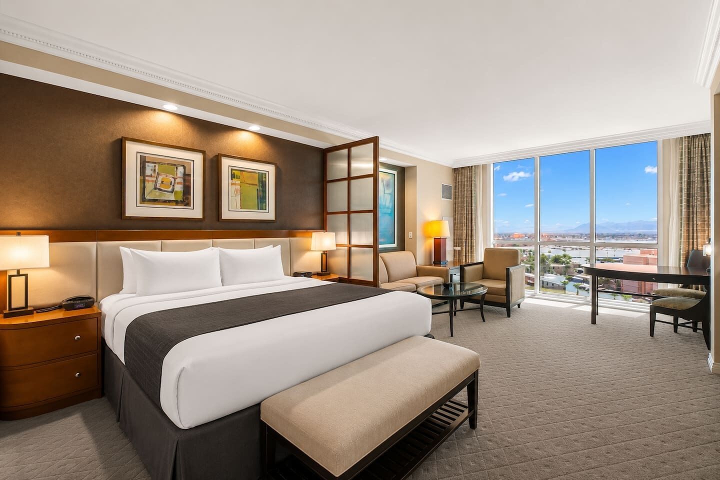 Habitación de hotel con una cama grande, un escritorio, una silla y vistas a la ciudad.