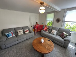 Ein Wohnzimmer mit zwei grauen Sofas, einem runden Couchtisch aus Holz und einem roten Spielbereich.