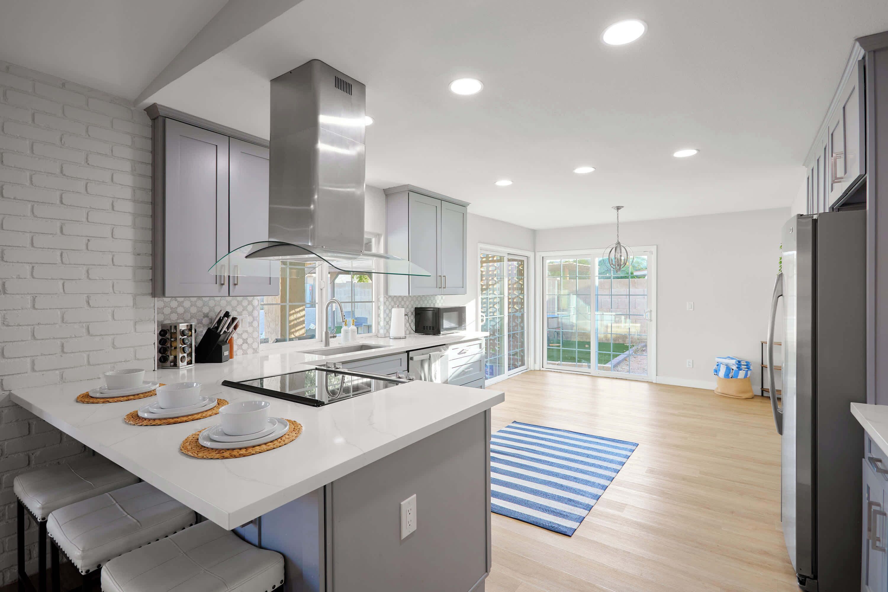A modern kitchen with a central island, white cabinetry, and a large window.