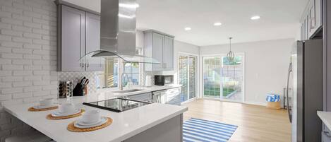 A modern kitchen with a central island, white cabinetry, and a large window.