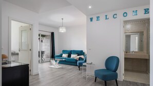 A modern living room with a blue sofa, a small round table, and a blue armchair. A 'WELCOME' sign is visible on the wall. - Ajuda VI – Comfortable Apartment in Funchal (Funchal)