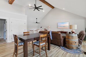 A dining area with a wooden table and chairs, a ceiling fan, and a view of the beach through a window. - A Stunning east facing, lake front home, in a cove, with Main Channel Views! (Sunrise Beach)