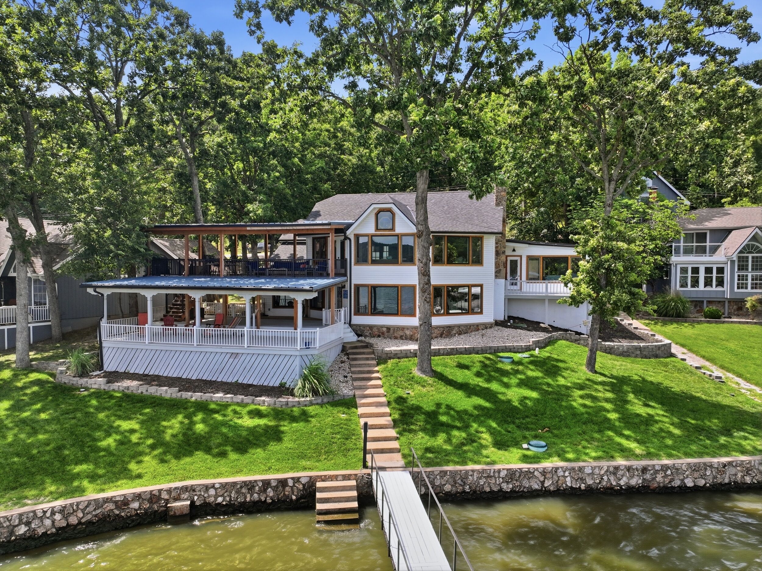 Ein zweistöckiges Haus mit überdachter Terrasse und einer Steinmauernuß.