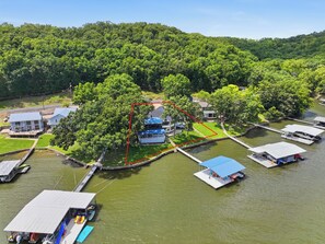 Une propriété située au bord de la rivière, avec des bateaux amarrés, une pelouse et une maison avec un toit bleu.