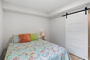 A bedroom with a bed, pillows, a nightstand, a lamp, and a sliding door. - A Stunning east facing, lake front home, in a cove, with Main Channel Views! (Sunrise Beach)