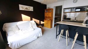 A bedroom with a bed, a desk, and a kitchenette. - Studio cosy avec coin cabine – Le Sauze (Enchastrayes)