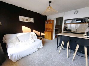 A bedroom with a bed, a desk, and a kitchenette. - Studio cosy avec coin cabine – Le Sauze (Enchastrayes)