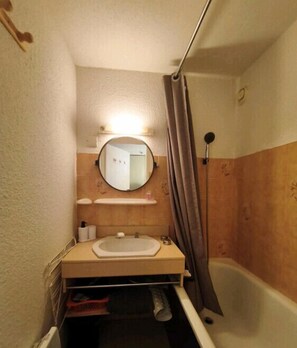 Ein kleines Badezimmer mit Waschbecken, Spiegel und Dusche.