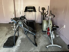 A home gym with a treadmill, elliptical, and stationary bike.
