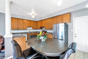 A modern kitchen with wooden cabinets, stainless steel appliances, and a dining table with chairs.