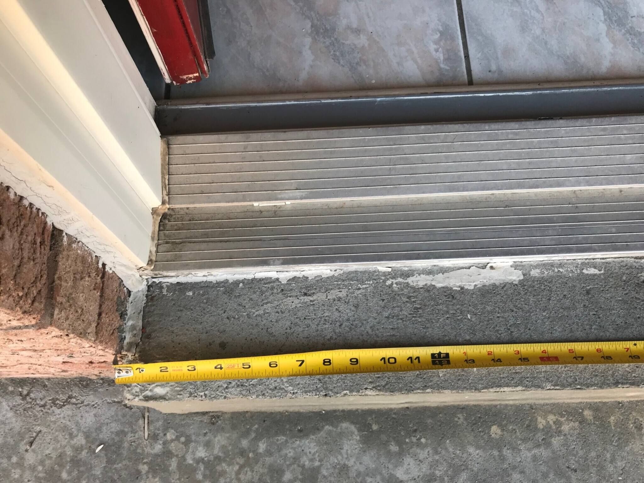 Un ruban à mesurer jaune, placé horizontalement sur une marche en béton, indique la hauteur de cette marche.