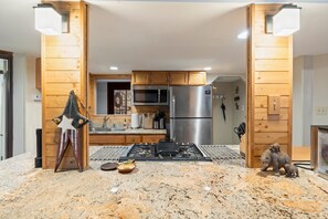 Eine Küche mit Holzausstattung, einem Edelstahl-Kühlschrank, einer Mikrowelle und einem Gasherd.