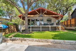 A two-story house with a covered patio, a stone staircase, and a fenced yard.