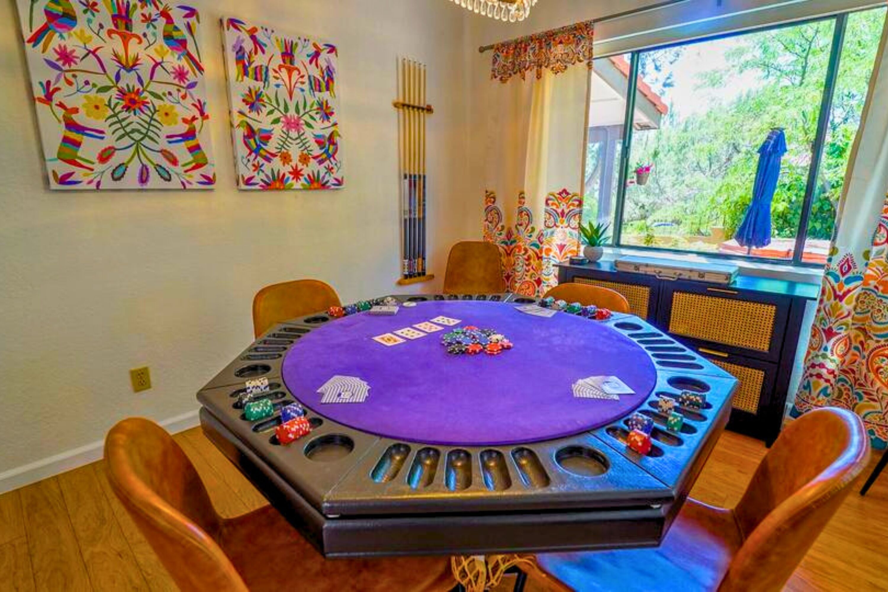 Ein Zimmer mit einem Pokertisch, Stühlen und farbenfroher Kunst an den Wänden.