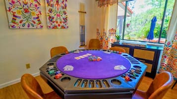 Una habitación con mesa de póker, sillas y coloridas obras de arte en las paredes.