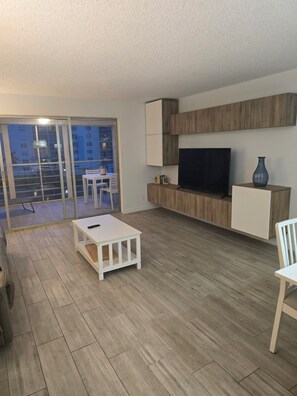 A modern living room with a flat-screen TV, a white coffee table, and a seating area with a sofa and chairs. - Spacious Dania Beach Condo Minutes from Beach, Airport & Cruise Port (Dania Beach)