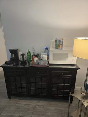 Un comptoir de cuisine avec une machine à café, un four à micro-ondes et une lampe.