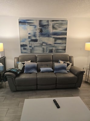 A living room with a gray sofa, a white coffee table, and a remote control on it. - Spacious Dania Beach Condo Minutes from Beach, Airport & Cruise Port (Dania Beach)
