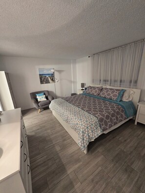 A bedroom with a bed, a chair, a desk, and a nightstand. - Spacious Dania Beach Condo Minutes from Beach, Airport & Cruise Port (Dania Beach)