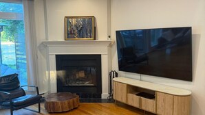 A modern living room with a fireplace, a large flat-screen TV mounted on the wall, and a wooden coffee table.
