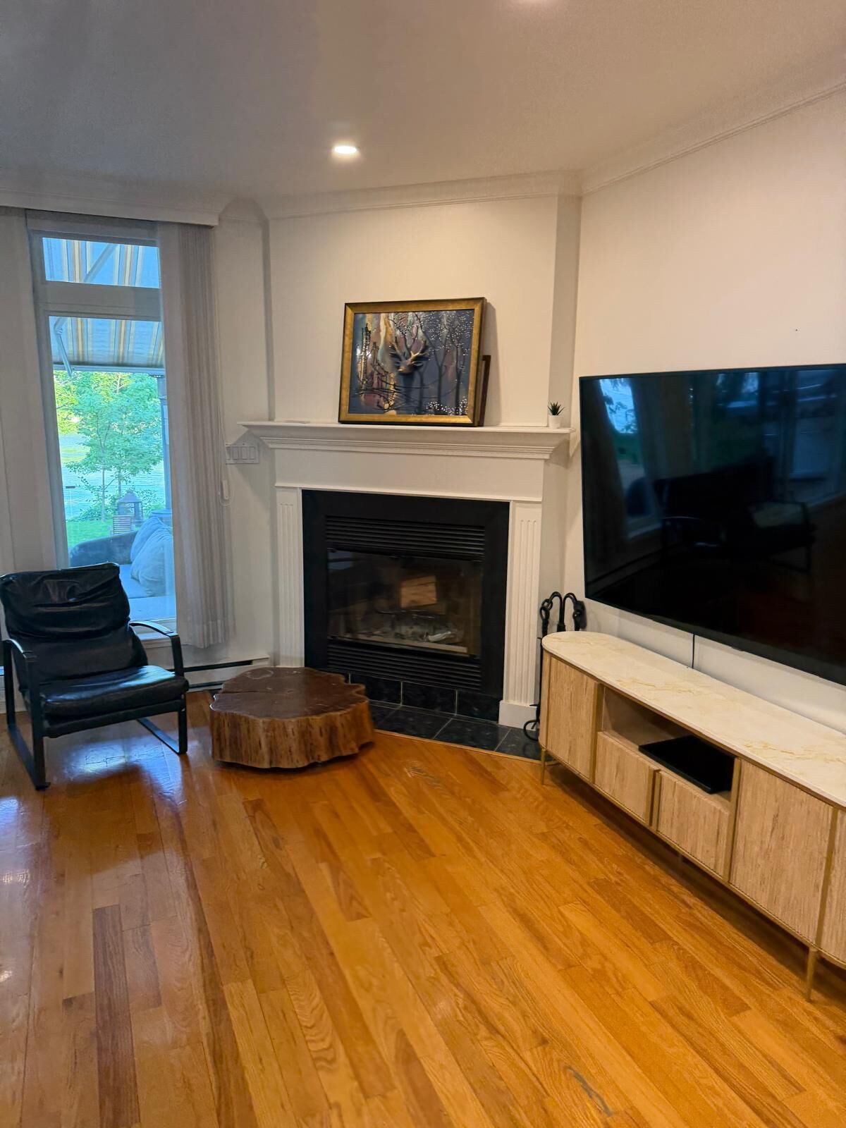 A living room with a fireplace, a television, and a large window.