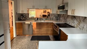 A modern kitchen with white cabinets, a marble backsplash, and a built-in oven.