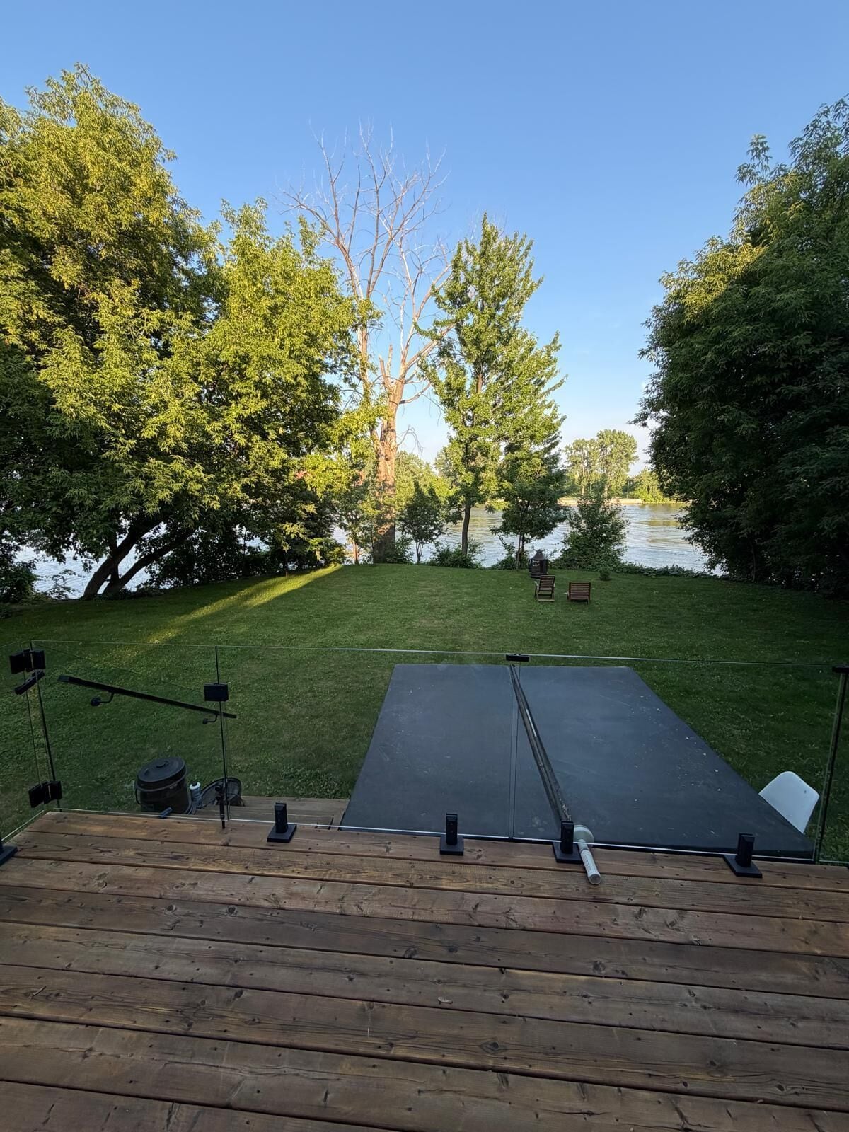 Una terraza con plataforma negra, rodeada de árboles y una masa de agua.