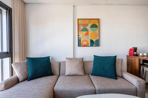 A neutral-colored sofa with teal cushions, a coffee machine, and a framed abstract artwork on the wall. - Charming Apartment 42 (Casablanca)