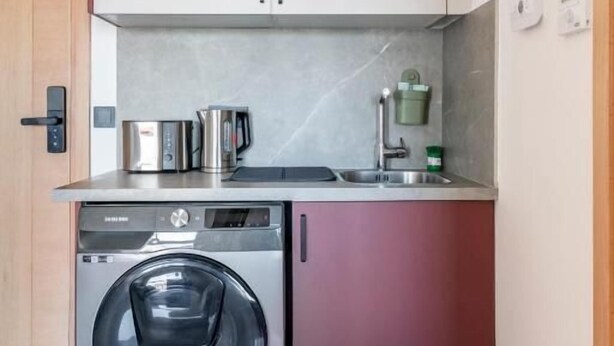 Cocina compacta con lavadora, cafetera y microondas.