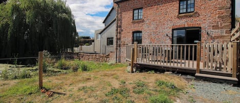 A brick building with a wooden deck and a stone wall.