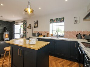 A modern kitchen with a central island, a built-in stove, and a large window providing natural light. - The Old Mill (Telford)