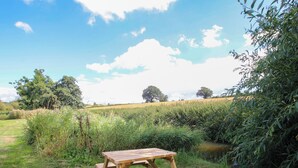 A picnic table in a grassy area with a pond and trees in the background. - The Old Mill (Telford)