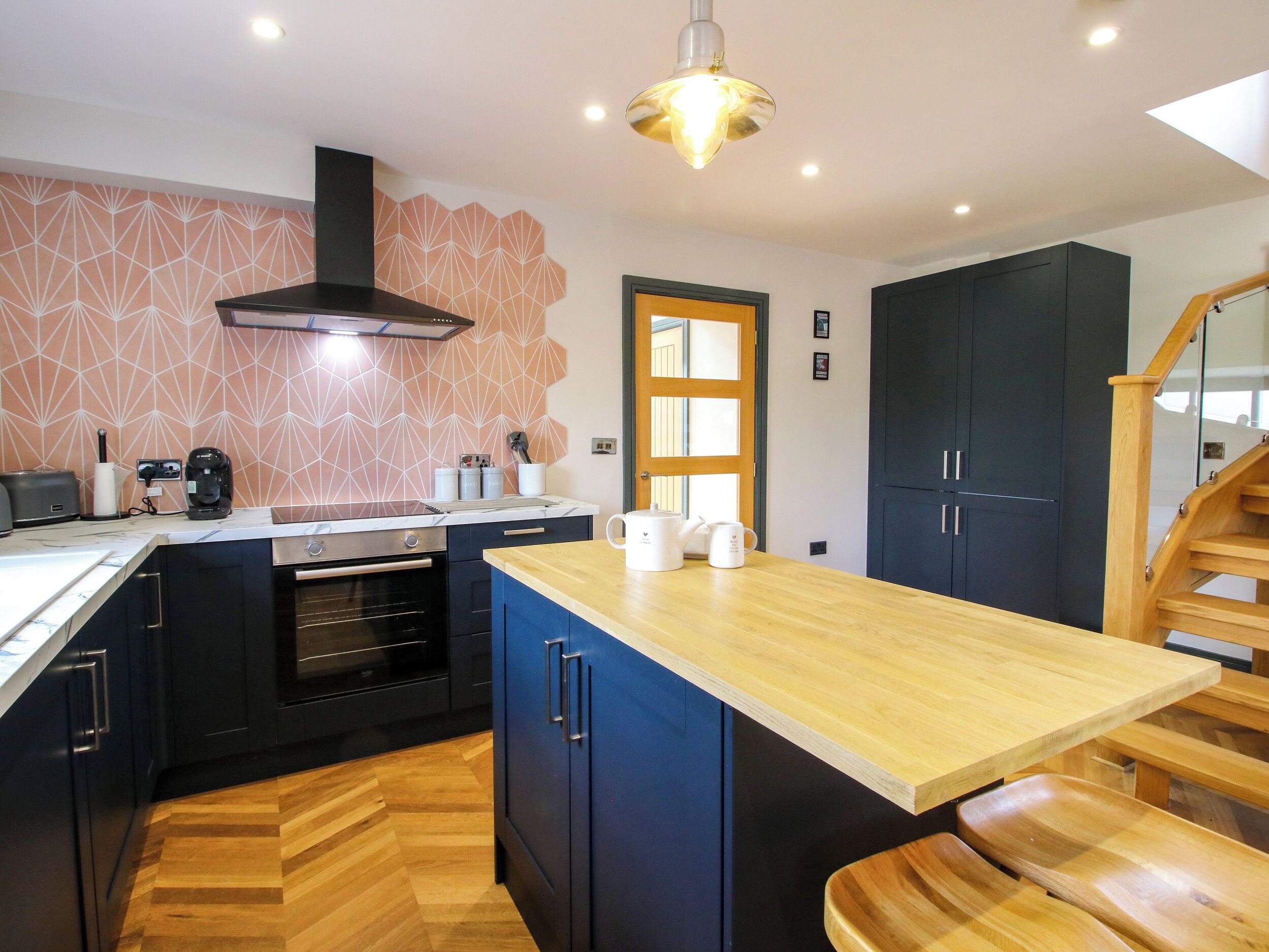 A modern kitchen with a central island, built-in oven, and a patterned backsplash.