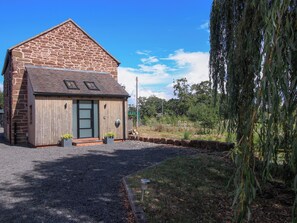 A stone building with a sloped roof, a wooden door, and a small attached shed. - The Old Mill (Telford)