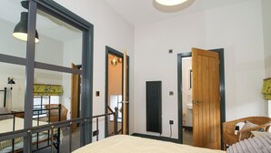 A bedroom with a bed, a window, a door, and a chair. - The Old Mill (Telford)