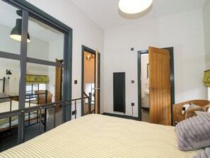Ein Schlafzimmer mit Bett, Fenster, Tür und Sessel.