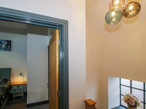 Ein Zimmer mit Holztür, einem Schreibtisch mit Lampe und einem Fenster mit Blick.