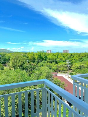 A balcony with a view of a green landscape and distant buildings.