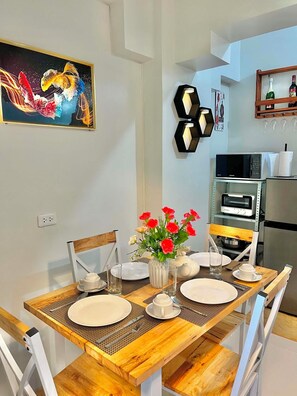A dining area with a wooden table set for four, surrounded by white chairs.
