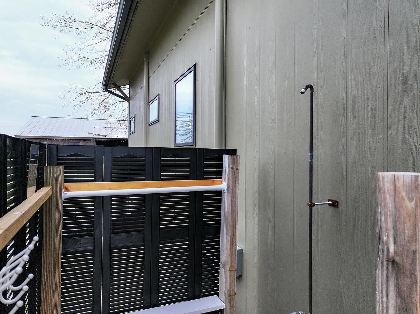 A building with a grey exterior, a black metal gate, and a wooden deck.
