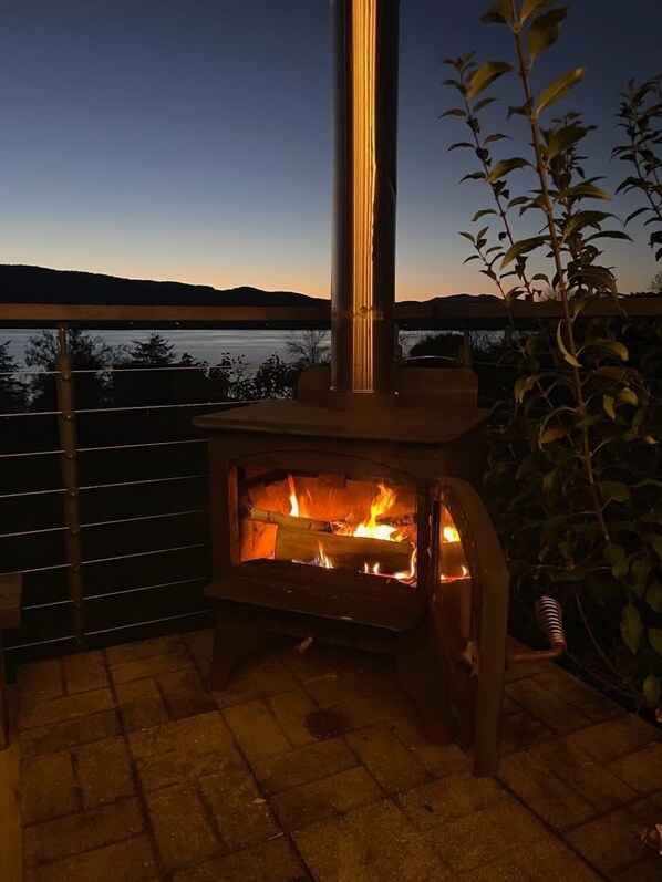 An outdoor wood-burning stove with a view of the landscape in the background.